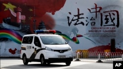 资料照:一辆警车驶过北京街头一堵宣传中国法治的宣传墙。(2016年12月28日)