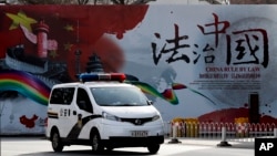 资料照:一辆警车驶过北京街头一堵宣传中国法治的宣传墙。(2016年12月28日)