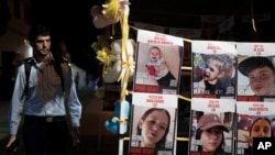 Співробітник ізраїльських сил безпеки дивиться на плакати із зображенням дітей, утримуваних ХАМАСом у заручниках у Секторі Гази, розміщені перед очікуваним звільнення заручників у Тель-Авіві, Ізраїль, 23 листопада 2023 р..