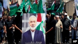 在黎巴嫩南部港口城市提尔的巴勒斯坦难民营,哈马斯成员举着哈马斯领导人伊斯梅尔·哈尼亚 (Ismail Haniyeh) 的画像抗议他被刺杀。(2024年7月31日)