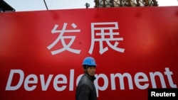 资料照:一名工人走过北京一处建筑工地的宣传标语。(2014年12月12日)