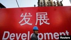 资料照:一名工人走过北京一处建筑工地的宣传标语。(2014年12月12日)