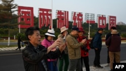 中国福建厦门竖立起一个台湾金门岛可以看到的“一国两制统一中国”的大型标语牌,旅游者在前拍照。(2024年1月12日)