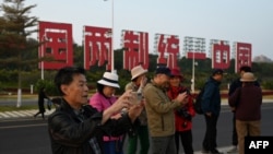 中国福建厦门竖立起一个台湾金门岛可以看到的“一国两制统一中国”的大型标语牌,游客在前拍照。(2024年1月12日)