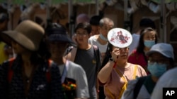 2023年6月22日,在中国正值人们庆祝端午节赛龙舟之时,然而气温却热得让人不可思议。一位来公园观看龙舟赛的妇女用扇子举在头上遮挡阳光。