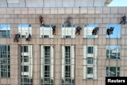 清洗高层建筑玻璃的工人继续在北京高温天气中工作。(2023年6月22日)