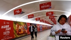 资料照:北京地铁乘客走过阿里巴巴为11月11日光棍节大促销所作广告的通道。(2023年10月26日)