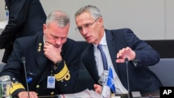 NATO Secretary-General Jens Stoltenberg, right, talks to Chair of the NATO Military Committee, Admiral Rob Bauer during a meeting of NATO defense ministers in the Ukraine Defense Contact Group format at NATO headquarters in Brussels, Oct. 12, 2022.