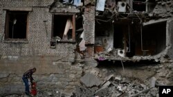 10月14日,在乌克兰东部康斯坦丁诺夫卡,一名居民正在清理遭到俄罗斯连夜炮击的房屋残骸。