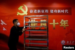 一名工作人员在北京一家酒店的中共二十大新闻中心走过宣传中国领导人习近平的标语。(2022年10月19日)