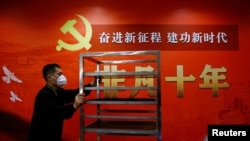 一名工作人员在北京一家酒店的中共二十大新闻中心走过宣传中国领导人习近平的标语。(2022年10月19日)