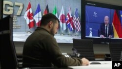 Ukrainian President Volodymyr Zelenskyy, left, and German Chancellor Olaf Scholz, right on the screen, attend the video conference of the leaders of the Group of Seven and Ukraine, in Kyiv, Ukraine, Oct. 11, 2022.