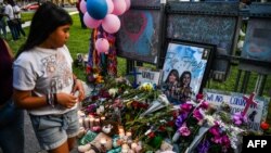 资料照片:一名女孩站在德克萨斯州尤瓦尔迪市法院外的纪念场地,几天前该市的罗伯小学发生了导致21人死亡的大规模枪击案。(2022年5月28日)