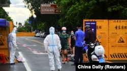 海南省三亚一个居民小区被封后快递员在小区门口递送食物。(2022年8月8日)