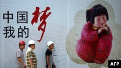 资料照:几名中国工人走过北京街头张贴的中国梦宣传画。(2013年9月2日)