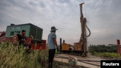 2022年8月27日,中国江西省九江市外,打井队队长高普察在打井,当地目前正在经历了一场严重干旱。