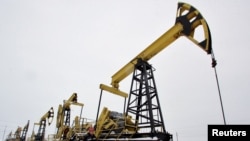 FILE - A worker walks past pump jacks at an oil field east of Izhevsk, Russia, Dec. 7, 2007.