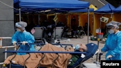 香港医护人员在一家医院外临时搭建的治疗区域移动一名新冠病人。(2022年2月28日)