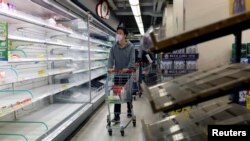 一名香港居民在一家超市空荡荡的货架前走过。(2022年2月28日)