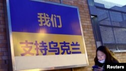 一名女子走过加拿大驻北京使馆外面挂出的支持乌克兰的标语牌(2022年3月2日)
