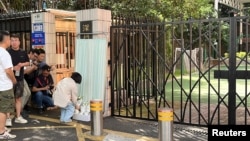 一名女子在广东省深圳的日本学校前放下一束鲜花。(2024年9月19日)