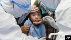 在武汉大规模检测 COVID-19 时,一名儿童正要做咽拭子检测。(2021年8月3日)