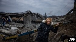 2022年3月7日,一名妇女从基辅西北部的伊尔平市撤离时穿过一座被毁的桥梁后休息(法新社)。