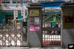 北京市朝阳区一所小学校的保安坐在紧闭的校门内。(2022年4月28日)