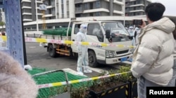 身穿防护服的警察站在运送绿色铁丝围栏的汽车旁。(2022年4月15日)