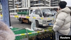 身穿防护服的警察站在运送绿色铁丝围栏的汽车旁。(2022年4月15日)