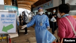 一名旅客在港珠澳大桥外与一名身穿防护服的工作人员交谈。(2022年12月23日)