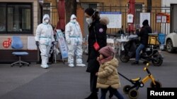 身穿防护服的大白站在北京一居民小区的大门处执勤。(2022年12月7日)