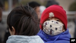 资料照 - 在北京闹市区,一对母子走在街上,母亲手里抱着的孩子在回头观望。