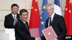 资料照:中国发改委主任何立峰与法国经济与财政部长布鲁诺·勒梅尔(右)在巴黎爱丽舍宫签署协议后,中国领导人习近平为其鼓掌。(2019年3月25日)