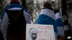 Russians with the Russian anti-war flags wrapped around them, take part in a protest against the Russian invasion of Ukraine in front of the Russian embassy in Vilnius, Lithuania, March 12, 2022.