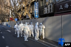 身穿防护服的工作人员在上海一处因发现新冠疫情而被封闭的小区的屏障外。(2022年3月15日)