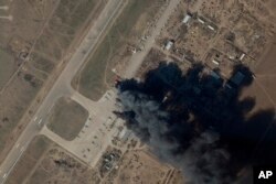 资料照片:Planet Labs PBC提供的卫星图片显示,在乌克兰军队据信发动空袭,摧毁了俄军直升机和坦克的一天后,赫尔松国际机场和空军基地冒出的烟火。(2022年3月15日)