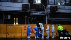 3月25日,身穿防护服的医务人员在上海一座被封闭小区的临时护墙外进行检查。