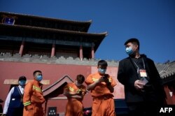 人们在北京紫禁城旁的一个新冠病毒核酸检测点旁排队等候进行检测。(2022年5月1日)