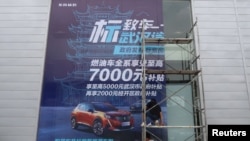 资料照:2020年8月9日,工人们在中国湖北省武汉市的一家经销店张贴了政府补贴东风标致汽车的巨幅海报。(路透社)