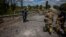 Soldiers of the Kraken Ukrainian special forces unit check a man's documents at a destroyed bridge on the road near the village of Rus'ka Lozova, north of Kharkiv, on May 16, 2022.