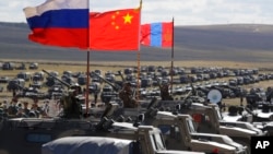 资料照:中国、俄罗斯和蒙古国军人手举各国国旗在俄罗斯西伯利亚参加联合军演。(2018你按9月13日)