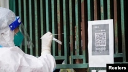 上海一名医务人员从一个固定新冠核酸采样点里给市民进行检测。(2022年5月5日)