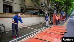 上海工人在拆除封闭街道的围栏。(2022年5月30日)