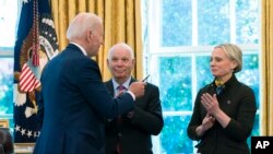 Президент Джо Байден передає ручку, яку він використав, коли підписував Акт про захист демократії в Україні від 2022 року, народженій в Україні Вікторії Спартц, штат Індія, 9 травня 2022 року у Вашингтоні. (AP Photo/Manuel Balce Ceneta)