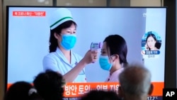 2022年5月14日,周六,在韩国首尔的一个火车站,人们正在观看有关朝鲜新冠肺炎疫情的新闻报道。