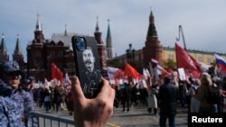 Офіцер російських правоохоронних органів тримає телефон із портретом радянського лідера Йосипа Сталіна під час маршу «Безсмертний полк» у День Перемоги, який відзначає 77-му річницю перемоги над нацистською Німеччиною у Другій світовій війні, у Москві, Росія, 9 травня 2022 року. REUTERS /Шаміль Жуматов
