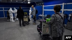 资料照:抵达上海浦东国际机场的旅客等候将要运载他们去隔离酒店的车辆。(2022年1月18日)