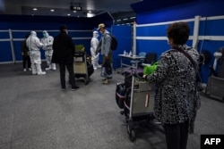 资料照:抵达上海浦东国际机场的乘客等候将要运载他们去隔离酒店的车辆。(2022年1月18日)