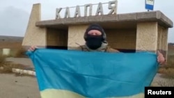 一名乌克兰士兵在南部赫尔松地区的一个村庄里展示乌克兰国旗。(2022年11月11日)